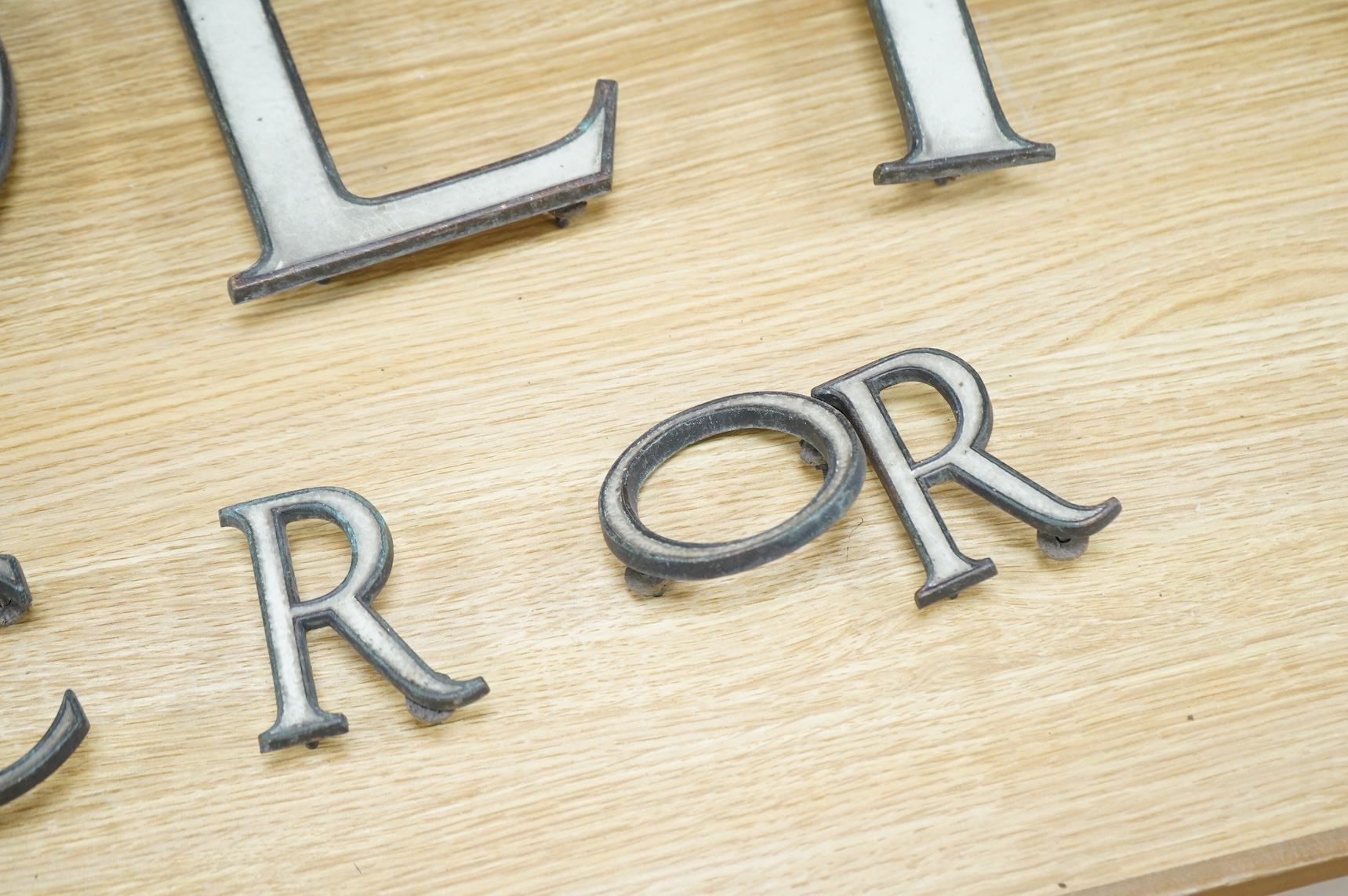 A part set of fifteen enamelled brass letters, largest 23cm
